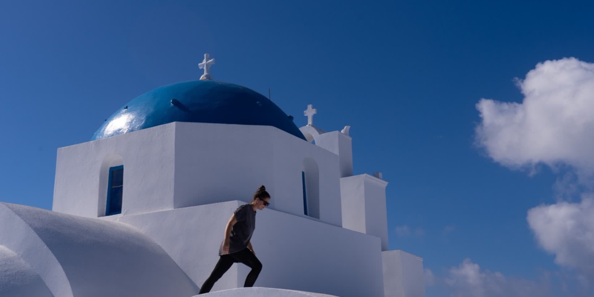 Frau vor einer weiss-blauen Kirche auf einer griechischen Insel